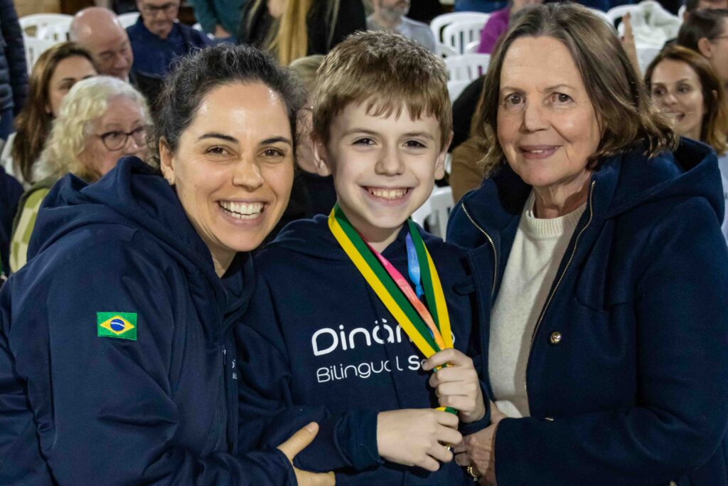 Alunos premiados na Canguru de Matemática celebram conquista ao lado de professoras, em evento com presença das famílias.